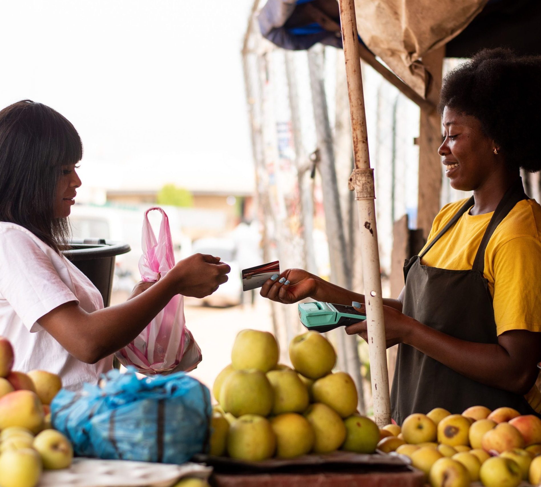african women in a market, paying with credit card